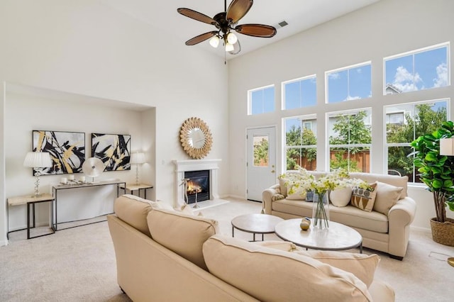 living room featuring a high ceiling, light carpet, and ceiling fan