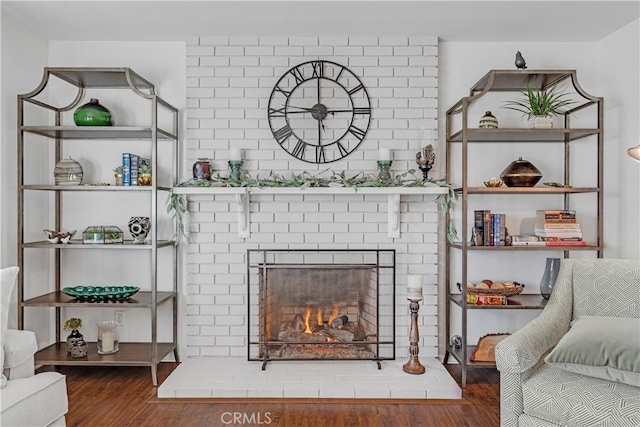 living room with dark wood-type flooring and a brick fireplace