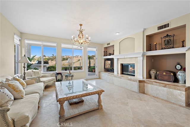 living room featuring built in shelves, a fireplace, and an inviting chandelier