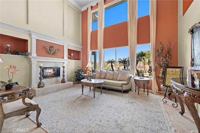 living room featuring crown molding, a premium fireplace, and a high ceiling