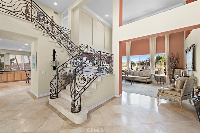 stairs featuring a high ceiling, crown molding, and tile patterned flooring