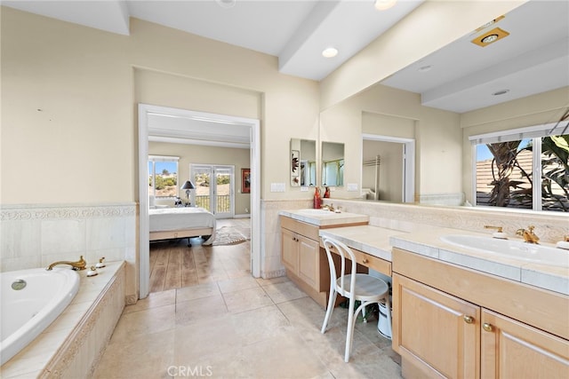 bathroom with tile patterned flooring, vanity, and tiled bath