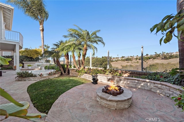 view of patio / terrace with a fire pit and a balcony