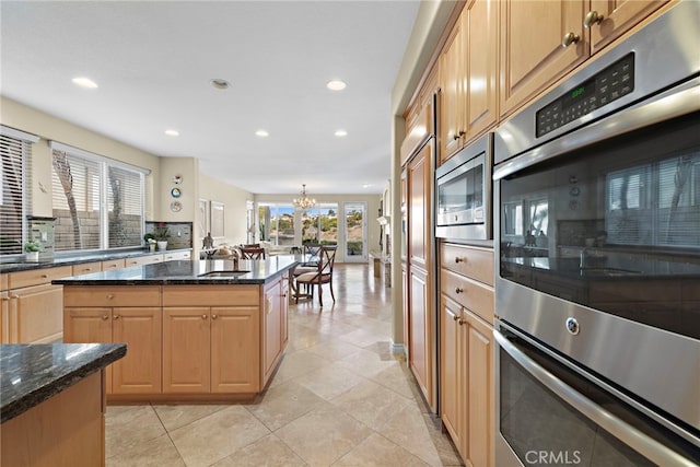 kitchen featuring plenty of natural light, stainless steel appliances, a center island, and dark stone counters