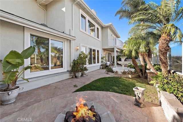 rear view of house with a balcony and an outdoor fire pit