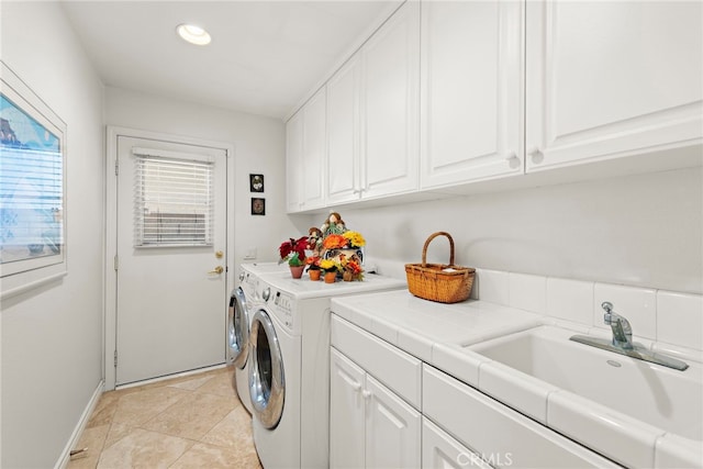 laundry room with cabinets, light tile patterned flooring, separate washer and dryer, and sink