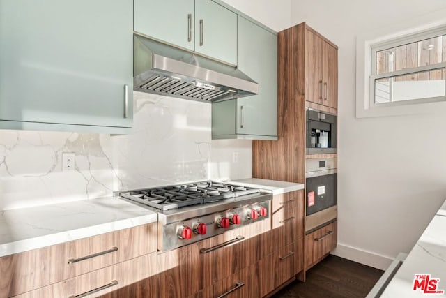 kitchen featuring stainless steel gas cooktop, light stone counters, dark hardwood / wood-style floors, green cabinets, and exhaust hood