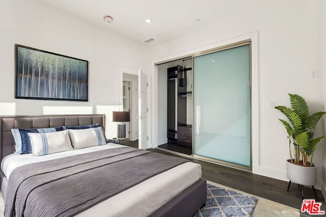 bedroom with dark wood-type flooring and a closet