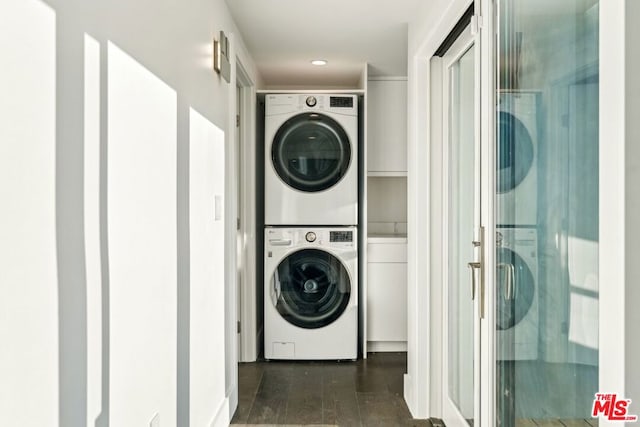 laundry area featuring stacked washer / drying machine and dark hardwood / wood-style floors