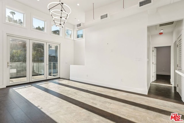 empty room featuring a high ceiling, dark wood-type flooring, and a chandelier