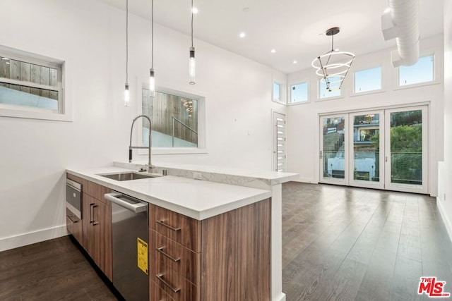 kitchen featuring dark hardwood / wood-style floors, decorative light fixtures, sink, stainless steel dishwasher, and kitchen peninsula