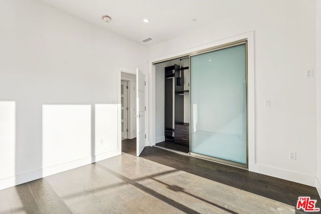 unfurnished bedroom featuring dark hardwood / wood-style flooring and a closet