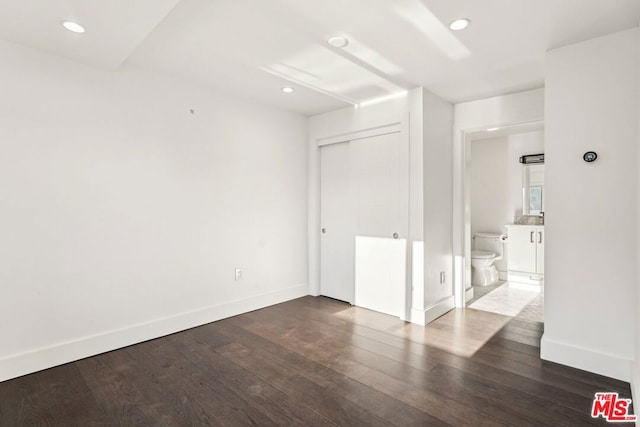 unfurnished bedroom featuring ensuite bathroom and dark wood-type flooring