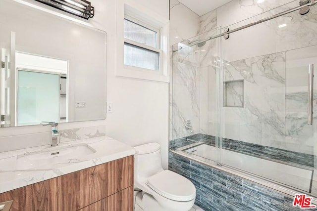 full bathroom featuring toilet, vanity, and bath / shower combo with glass door