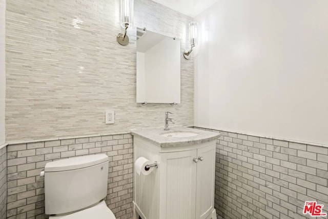 bathroom featuring vanity, tile walls, and toilet