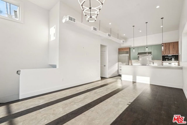 living room with wood-type flooring, a towering ceiling, and a notable chandelier