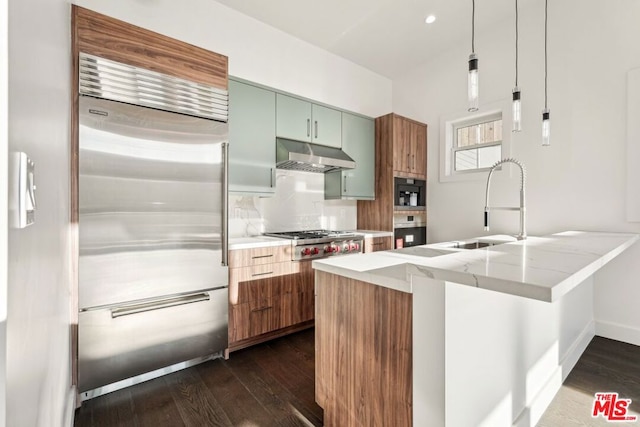 kitchen with sink, green cabinets, appliances with stainless steel finishes, light stone counters, and kitchen peninsula