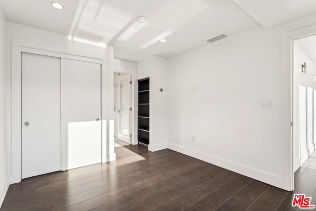 unfurnished bedroom featuring dark hardwood / wood-style flooring and a closet