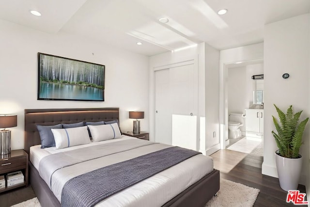 bedroom featuring ensuite bathroom and dark hardwood / wood-style floors