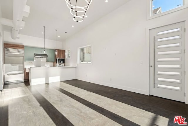 kitchen featuring built in fridge, a towering ceiling, pendant lighting, a chandelier, and decorative backsplash