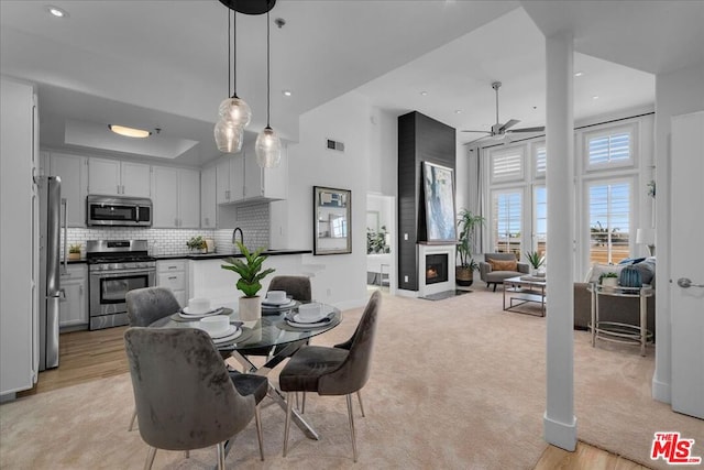 carpeted dining room with ceiling fan and a towering ceiling