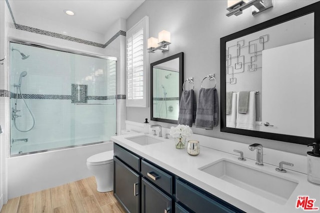 full bathroom with vanity, combined bath / shower with glass door, wood-type flooring, and toilet