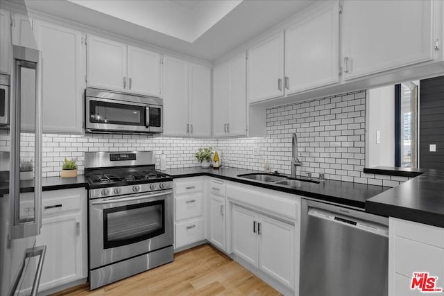 kitchen featuring sink, tasteful backsplash, light hardwood / wood-style flooring, appliances with stainless steel finishes, and white cabinets