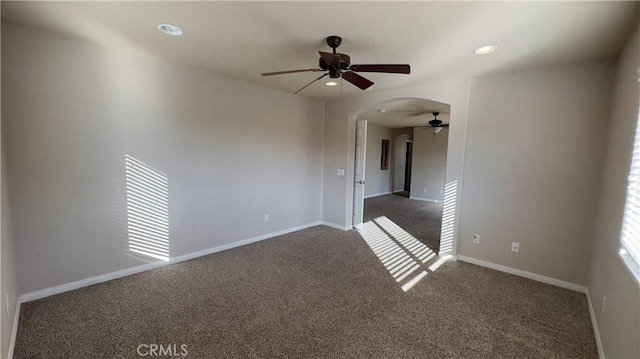 spare room with ceiling fan and dark colored carpet