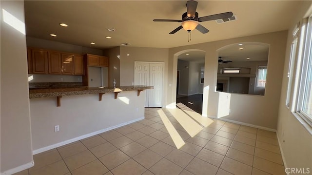 kitchen featuring a breakfast bar, light tile patterned floors, ceiling fan, and kitchen peninsula