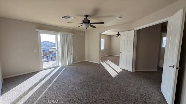 spare room featuring dark colored carpet and ceiling fan