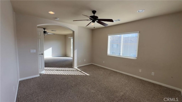 empty room featuring ceiling fan and dark colored carpet