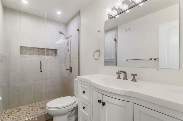 bathroom featuring vanity, toilet, and a shower with shower door