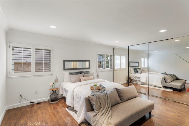 bedroom with wood-type flooring, crown molding, and a closet