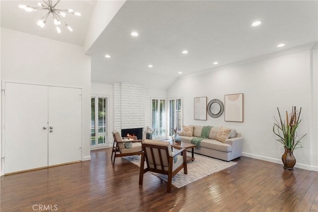 living room with lofted ceiling, a notable chandelier, a fireplace, and dark hardwood / wood-style floors