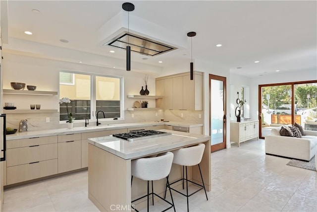 kitchen featuring a kitchen island, decorative light fixtures, stainless steel gas stovetop, sink, and decorative backsplash