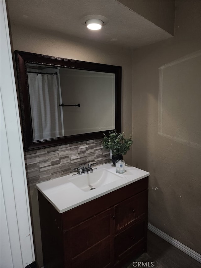 bathroom featuring tasteful backsplash, vanity, and baseboards