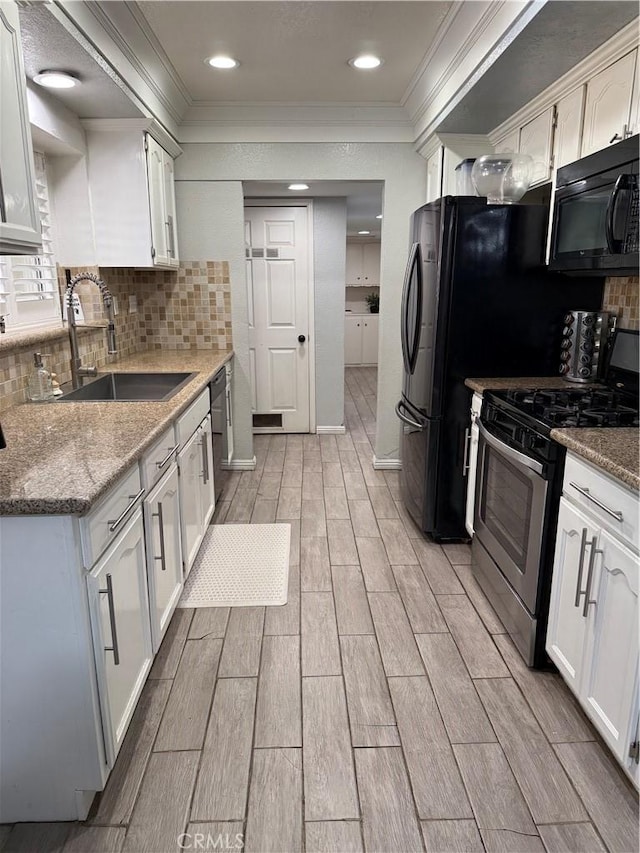 kitchen featuring wood tiled floor, white cabinets, a sink, black microwave, and stainless steel gas range oven