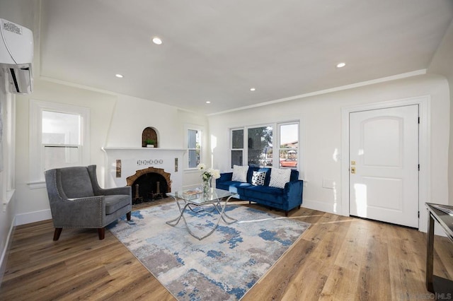 living room featuring wood-type flooring, a brick fireplace, and an AC wall unit