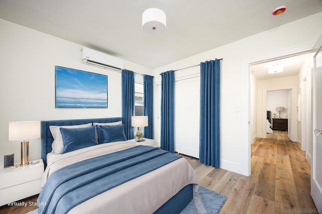 bedroom with a wall unit AC and light hardwood / wood-style floors