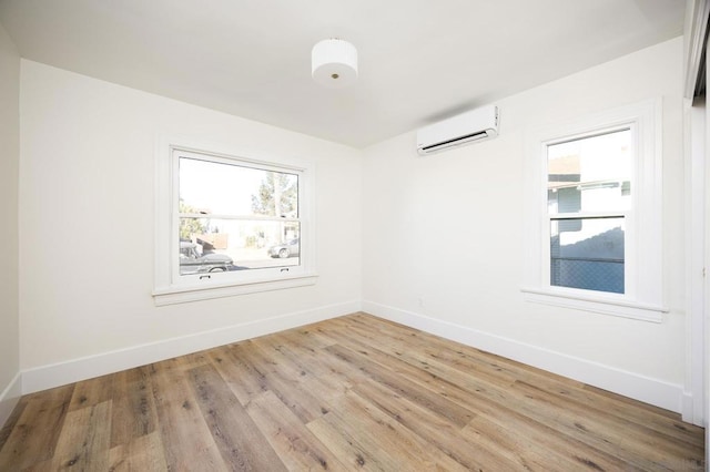 spare room with a wall unit AC and light hardwood / wood-style floors