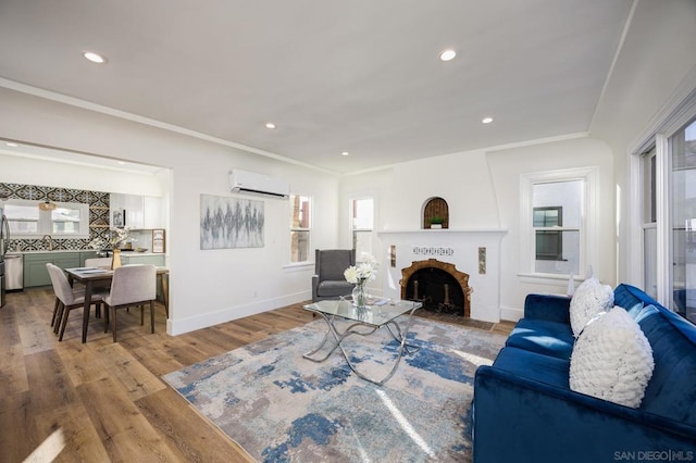 living room featuring plenty of natural light, sink, a wall mounted air conditioner, and light hardwood / wood-style flooring