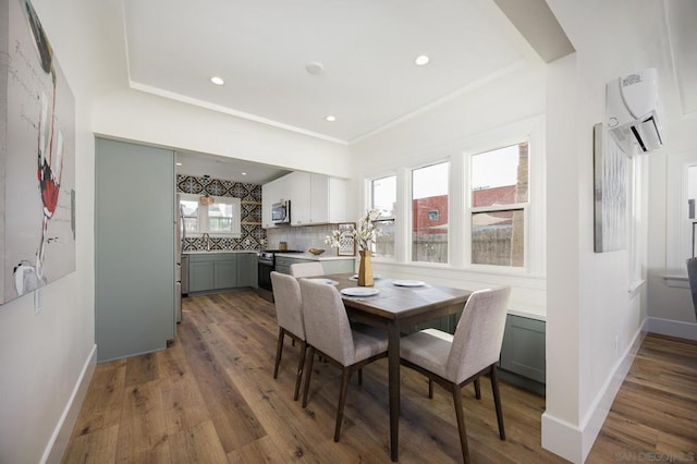 dining area with hardwood / wood-style flooring, sink, and a wall unit AC