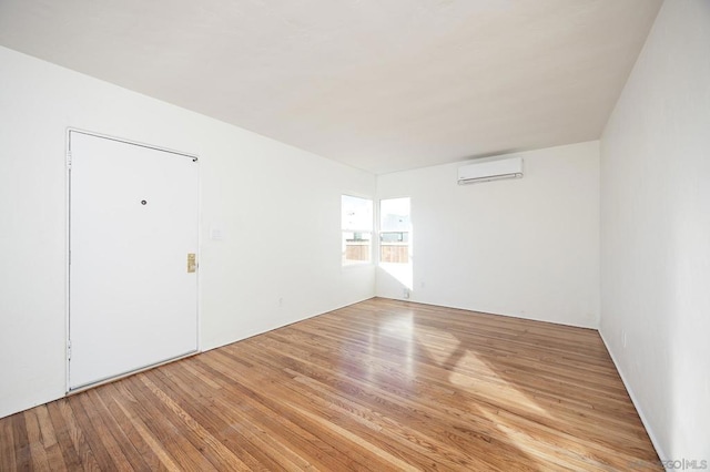 spare room featuring light hardwood / wood-style flooring and a wall unit AC