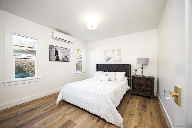 bedroom featuring multiple windows, hardwood / wood-style flooring, and an AC wall unit