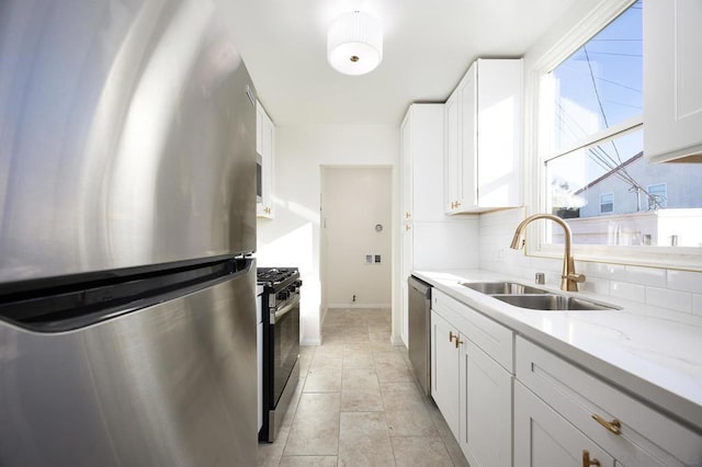 kitchen featuring sink, tasteful backsplash, appliances with stainless steel finishes, light stone countertops, and white cabinets