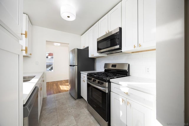 kitchen with backsplash, stainless steel appliances, light tile patterned floors, and white cabinets