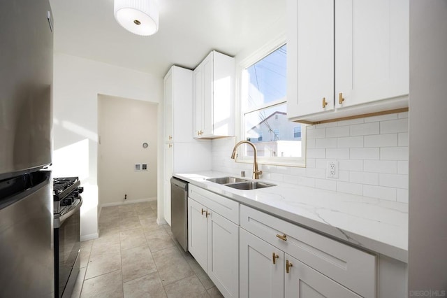 kitchen with sink, light stone counters, white cabinetry, light tile patterned floors, and stainless steel appliances