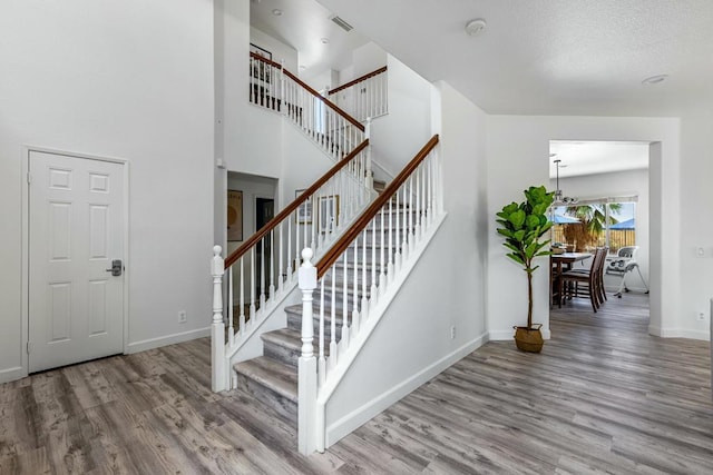 staircase with hardwood / wood-style flooring and a towering ceiling