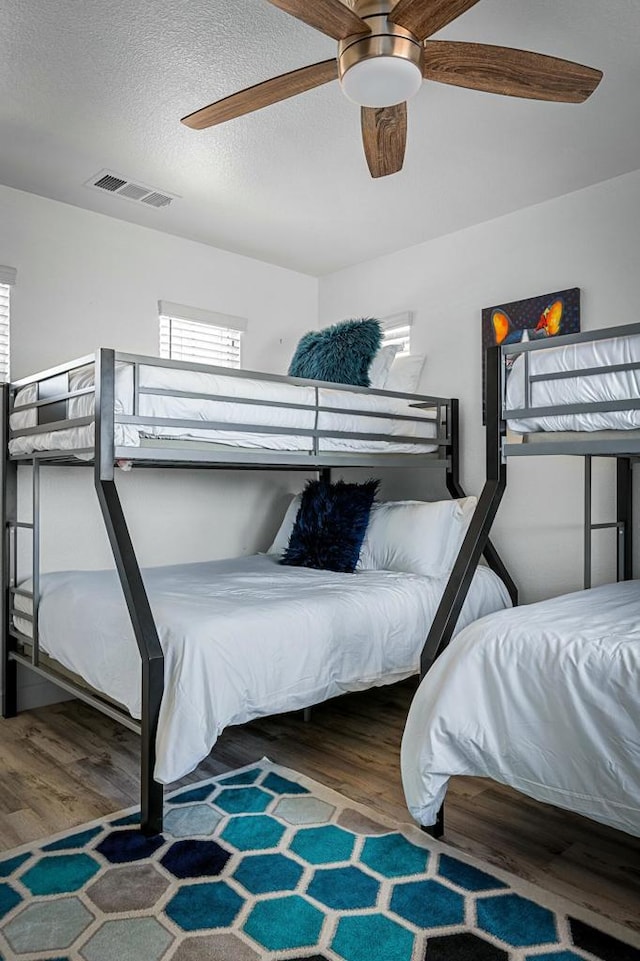 bedroom featuring a textured ceiling, wood-type flooring, and ceiling fan