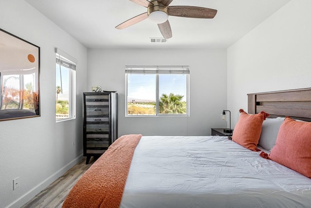 bedroom featuring multiple windows, light hardwood / wood-style flooring, beverage cooler, and ceiling fan